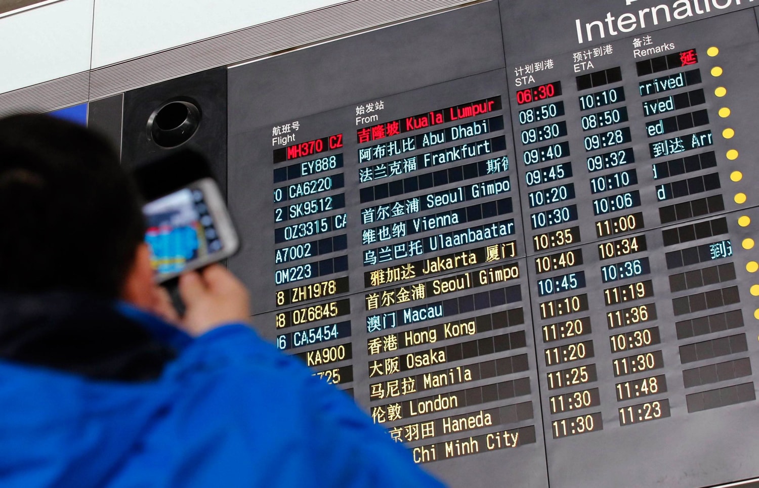 Image: A man takes pictures of a flight information board