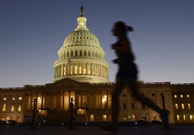 Image: A jogger runs by as night falls on the U.S. Capitol on the eve of a potential government shutdown.