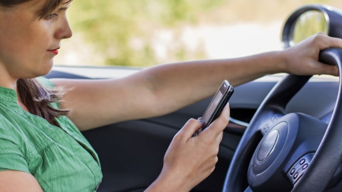 Woman driver reading a text message on a mobile
