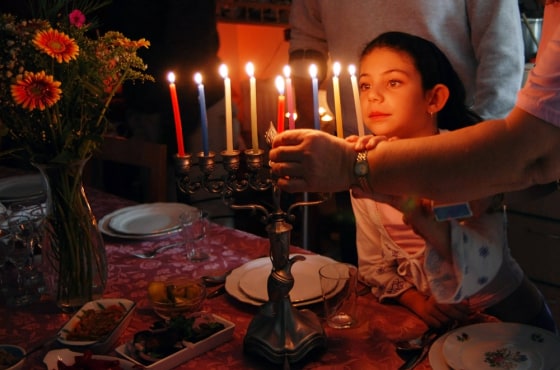 A family is lighting a candle for the Jewish holiday of Hanukkah.; candle; candlestick; celebrate; celebrating; celebration; channukah; chanuka; chanu...
