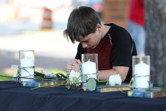 Image: A young boy prays during a vigil held at the Texas First Bank after a shooting left several people dead at Santa Fe High School in Santa Fe, Texas