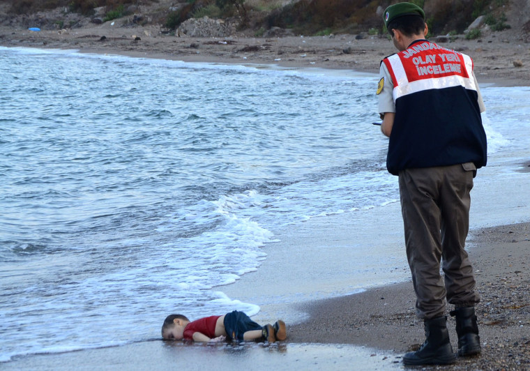Image: A Turkish police officer stands next to the body of Aylan Kurdi in 2015