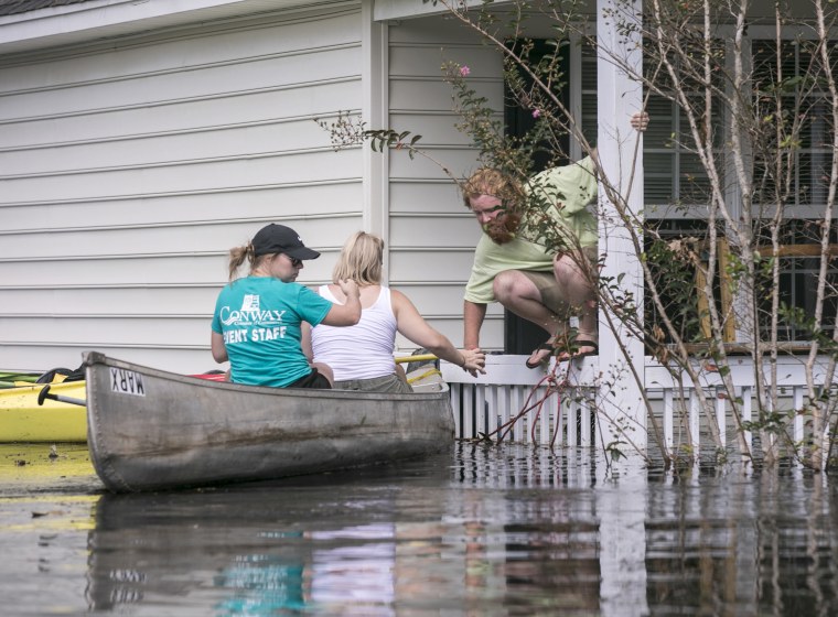David Covington jumps from a porch railing to his canoe along with Maura Walbourne and her sister Katie Walborne in Conway, South Carolina, on Sept. 23, 2018. The three paddled a canoe to Covington's home on Long Avenue on Sunday to find it flooded and the floor boards floating.