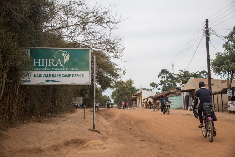 Image: A refugee cycles past a sign pointing to the office of one of UNHCR's implementing partners in Nakivale refugee settlement.