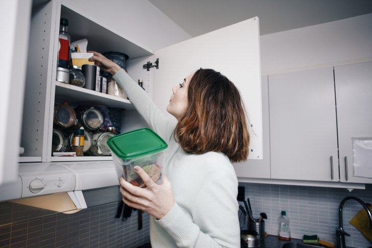 Young woman searching in cabinet at kitchen