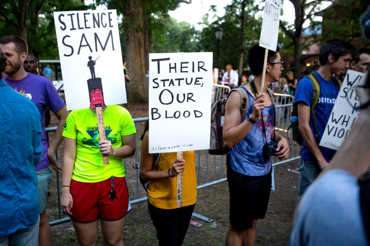 Protesters hold signs during a rally over Silent Sam on Aug. 30, 2018.