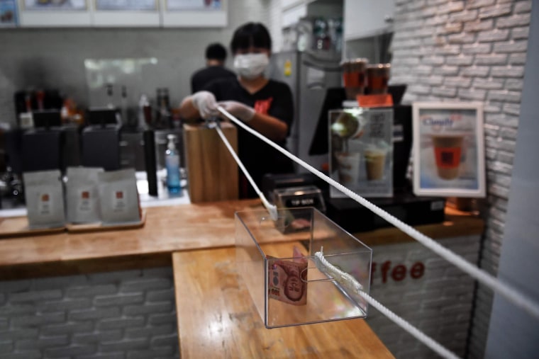 Image: A barista from the "Art Of Coffee" cafe uses a pulley system to accept cash for a cup of coffee from a customer, in an effort to practise social distancing amid concerns over the spread of the COVID-19 coronavirus, in Bangkok