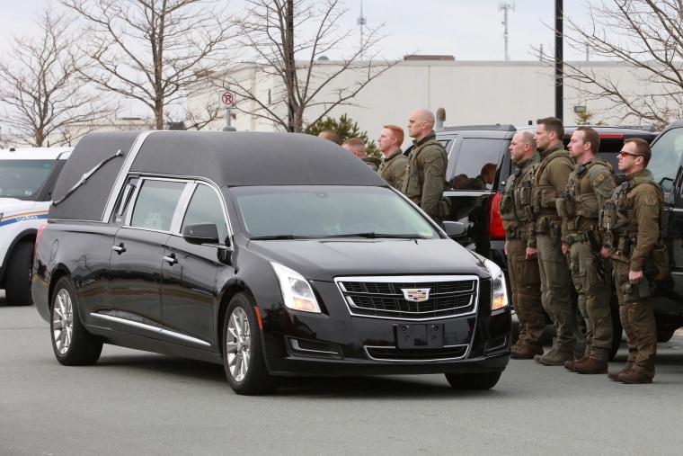 RCMP officers stand as a hearse carrying the body of Constable Heidi Stevenson passes in Dartmouth