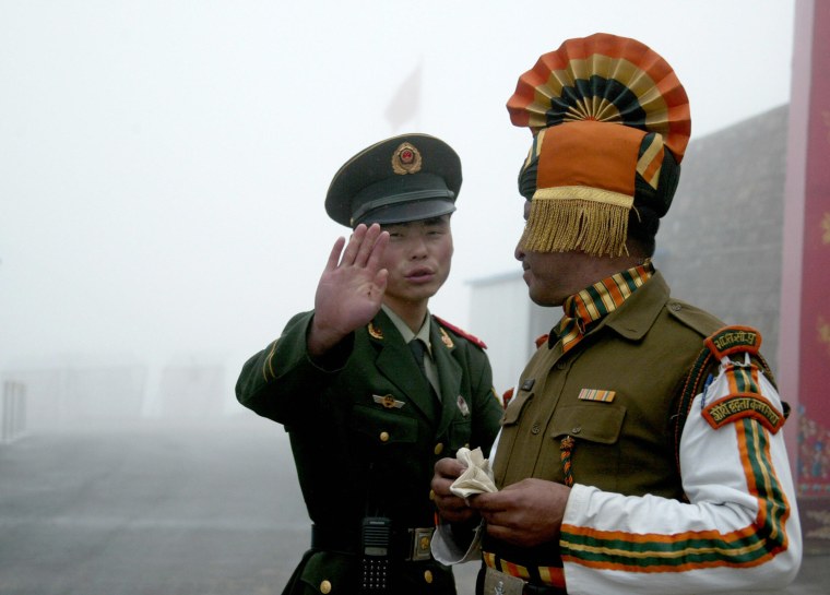Image: A Chinese soldier gestures as he stands near an Indian soldier on the Chinese side of the ancient Nathu La border crossing between India and China.