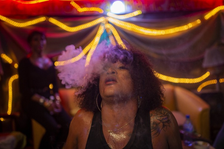 Image: Transgender Laurent Voltus, a resident at the Kay Trans Haiti center, exhales cigarette smoke while dancing with friends at a club in Port-au-Prince, Haiti