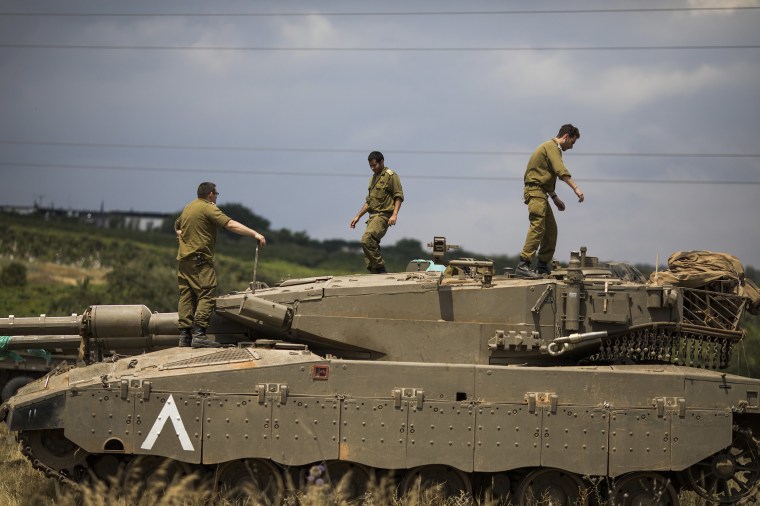 Image: Israeli soldiers on top of a Merkava Mark IV tank that deployed along the border with Syria, in Golan Heights, Israel.