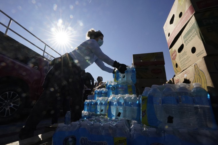 Image: Volunteers load water for people at a San Antonio Food Bank drive-through food distribution site